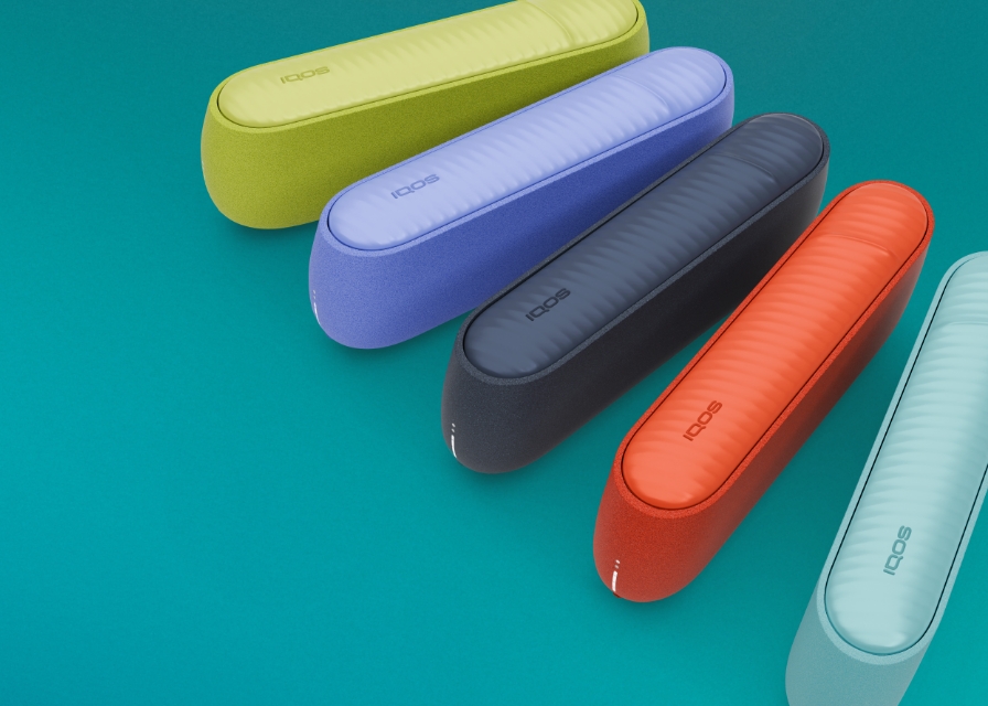 Equipamentos IQOS ILUMA i na cor verde, violeta, azul escuro, terracota e azul claro alinhados concentricamente ao canto superior direito, em fundo azul 