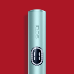 Dispositivo IQOS ILUMA i azul claro sobre fundo vermelho, com detalhe do ecrã tátil