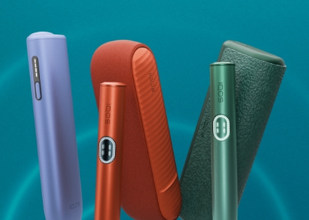 Equipamento IQOS ILUMA i ONE violeta orientado para a esquerda, equipamento IQOS ILUMA i terracota ao centro e equipamento IQOS ILUMA i PRIME verde orientado para a direita, em fundo azul com efeito luminoso