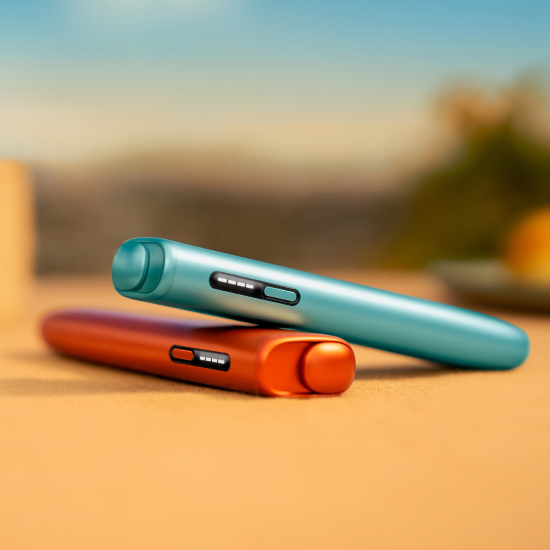 Dispositivo ILUMA i ONE Azul Claro sobre dispositivo IQOS ILUMA i ONE Terracota  em fundo com ambiente exterior desfocado