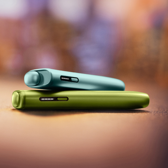 Dispositivo IQOS ILUMA i ONE Azul Claro sobre dispositivo IQOS ILUMA i ONE Verde, em fundo desfocado