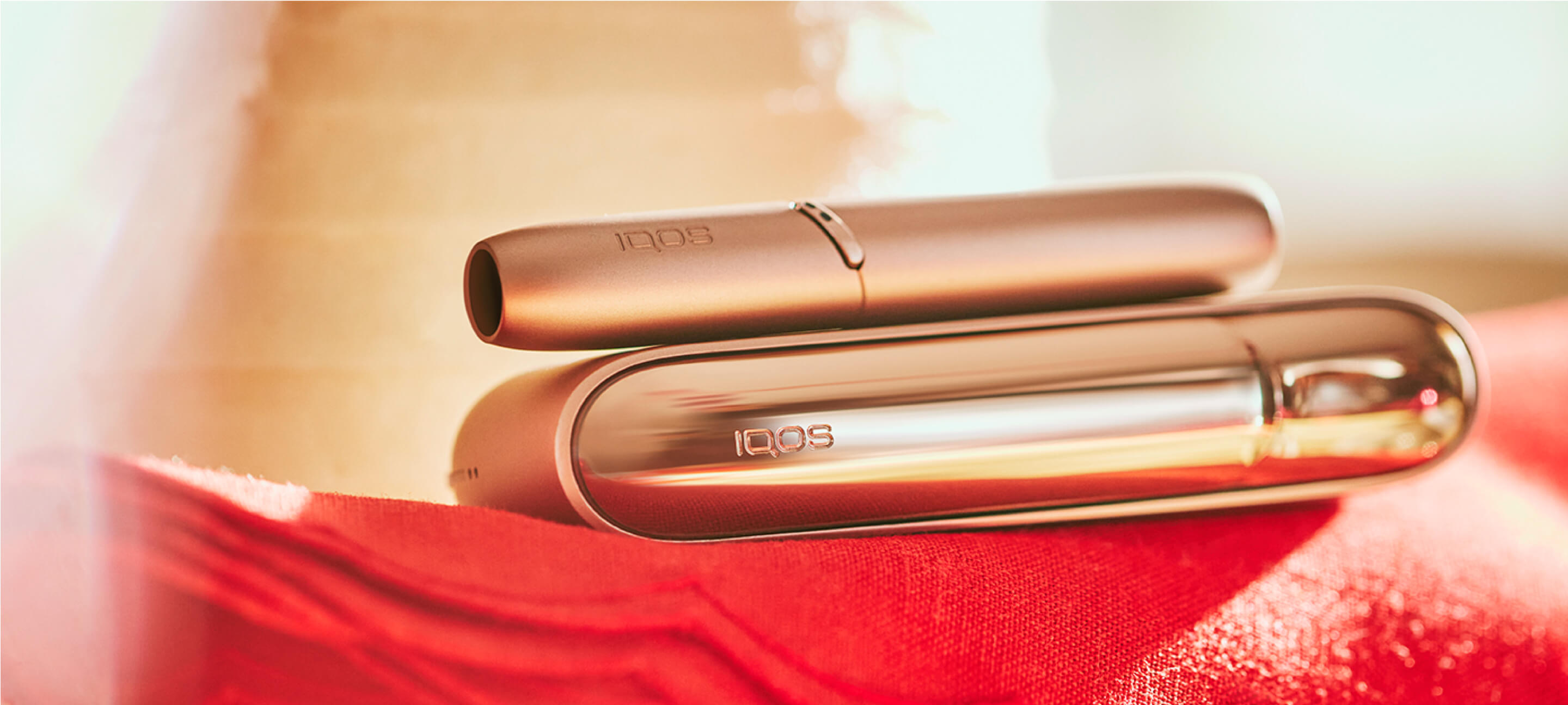 Um IQOS 3 DUO Dourado num tecido vermelho