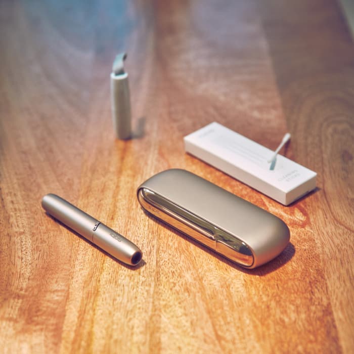 Cups, an IQOS device and a mobile on a table