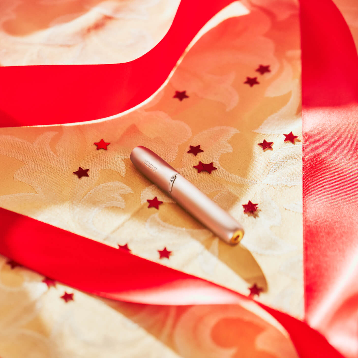 Brilliant gold IQOS 3 DUO holder inserted on fabric with red stars