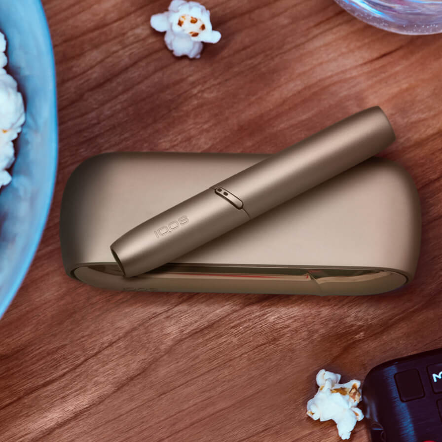 Dispositivo IQOS ao lado de um balde de pipocas