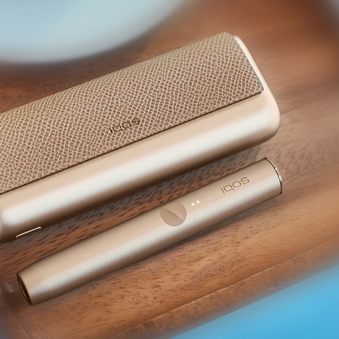 Um equipamento IQOS ILUMA PRIME por cima de uma guitarra.
