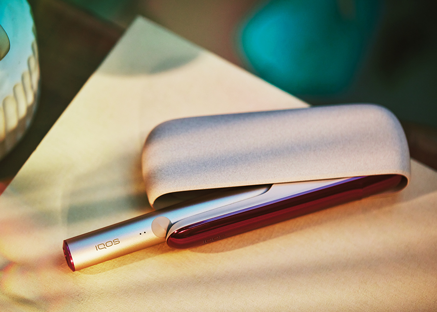 Brilliant gold IQOS 3 DUO holder inserted on fabric with red stars