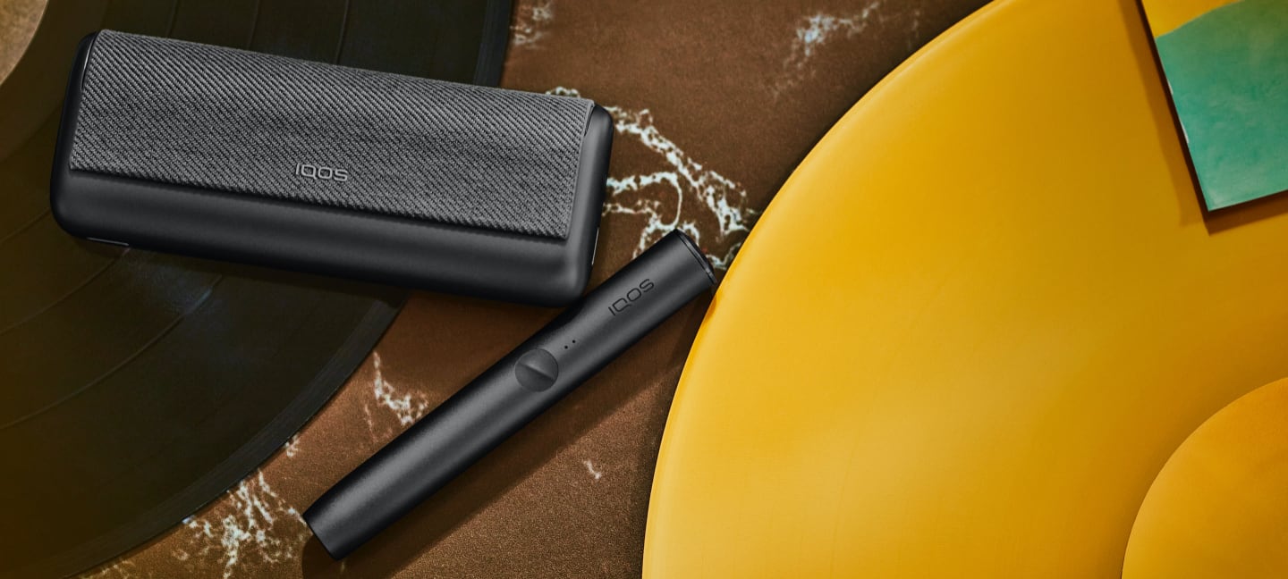 Um dispositivo IQOS ILUMA PRIME preto com uma aba integral a combinar.