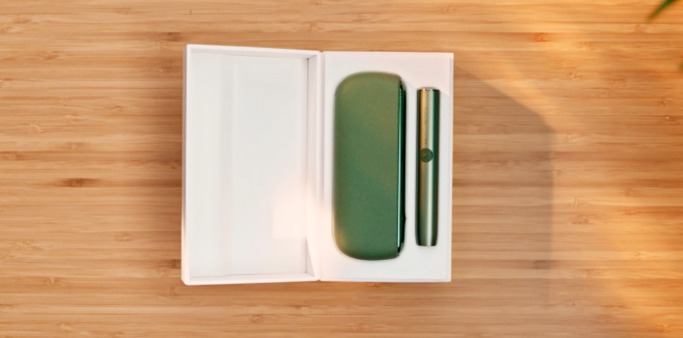 A Moss Green IQOS ILUMA holder and Pocket Charger in a box.