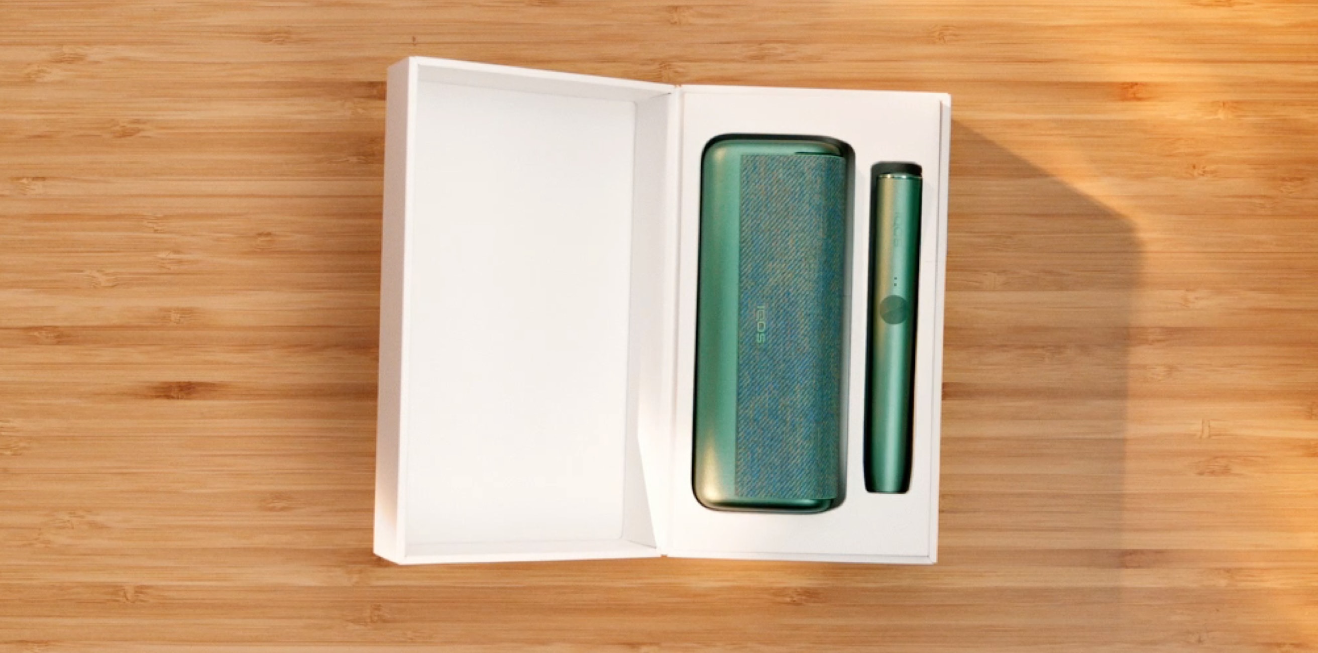 A Jade Green IQOS ILUMA PRIME holder and Pocket Charger in a box.