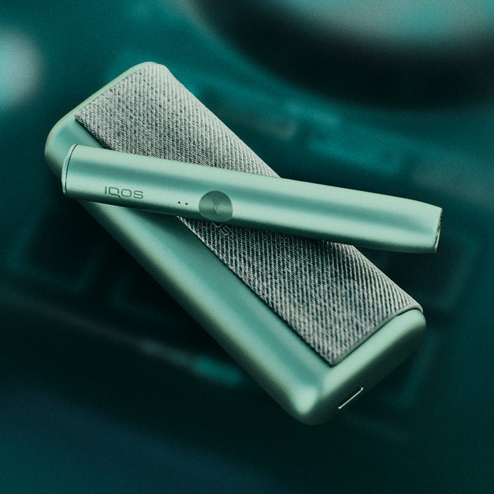 A jade green IQOS ILUMA device and charger.