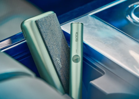 A jade green IQOS ILUMA device and holder.