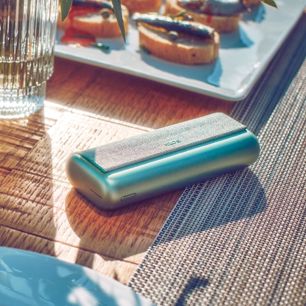 A Jade Green IQOS ILUMA PRIME Pocket Charger on a table.