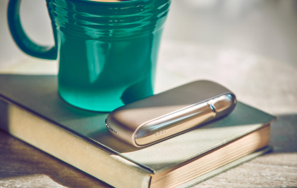 A gold IQOS holder on a closed book.