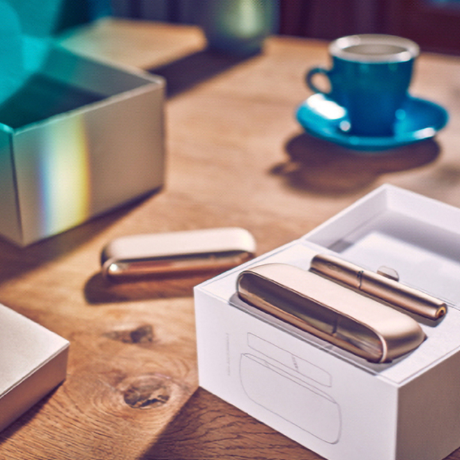 A Moss Green IQOS device sitting on a car console.
