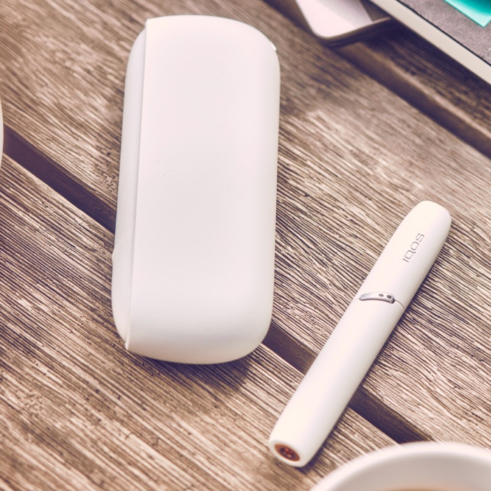 White IQOS 3 DUO holder and charger on a picnic table