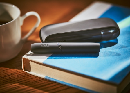 Black IQOS device on a blue book