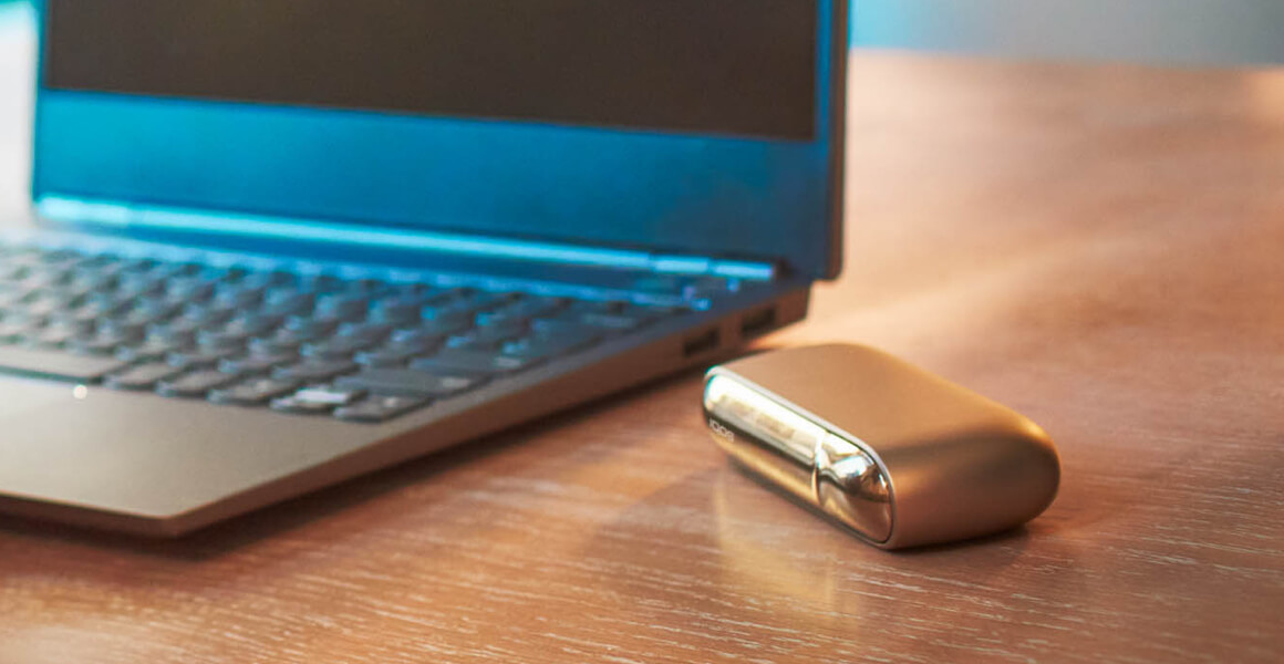 Blue laptop and an IQOS device on the table