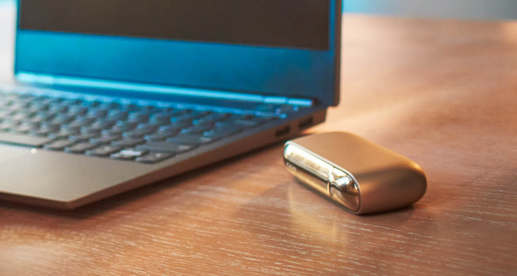 Blue laptop and an IQOS device on the table