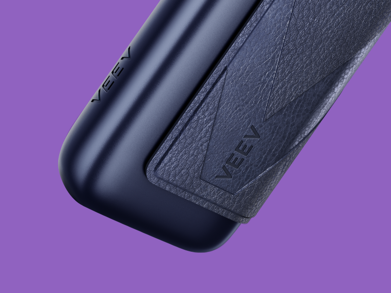 Dispositivo aproximado VEEV ONE PLUS em preto, parte inferior, com  logótipo e luzes de estado acesas e botão, orientado para direita, em fundo roxo.